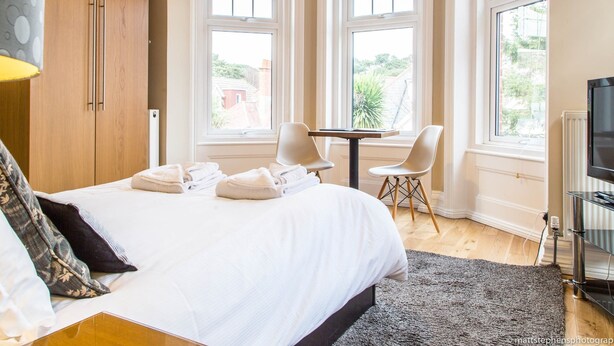 A hotel room with a bed, two chairs, a table, and a TV.