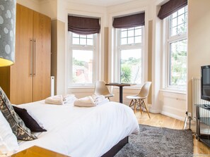 A hotel room with a bed, two chairs, a table, and a TV. - Alum Chine Beach House (Bournemouth)