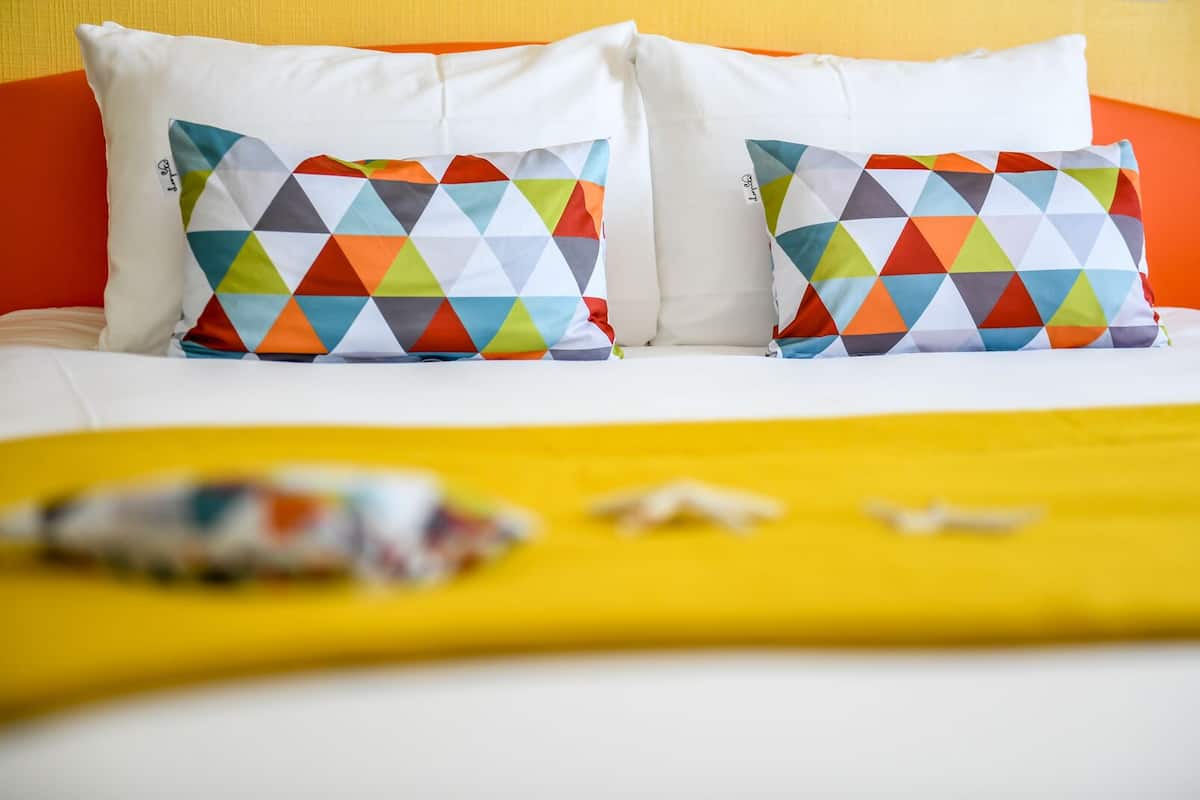 Una cama con ropa de cama blanca y almohadas de diseños geom étricos coloridos.