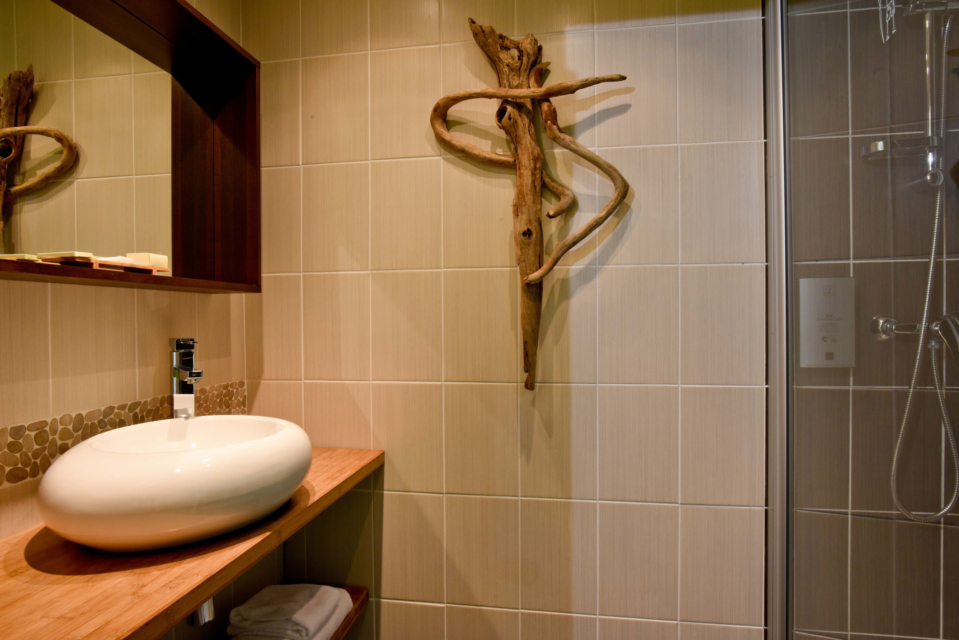 Un baño con tocador de madera, lavamanos blanco y zona de ducha.