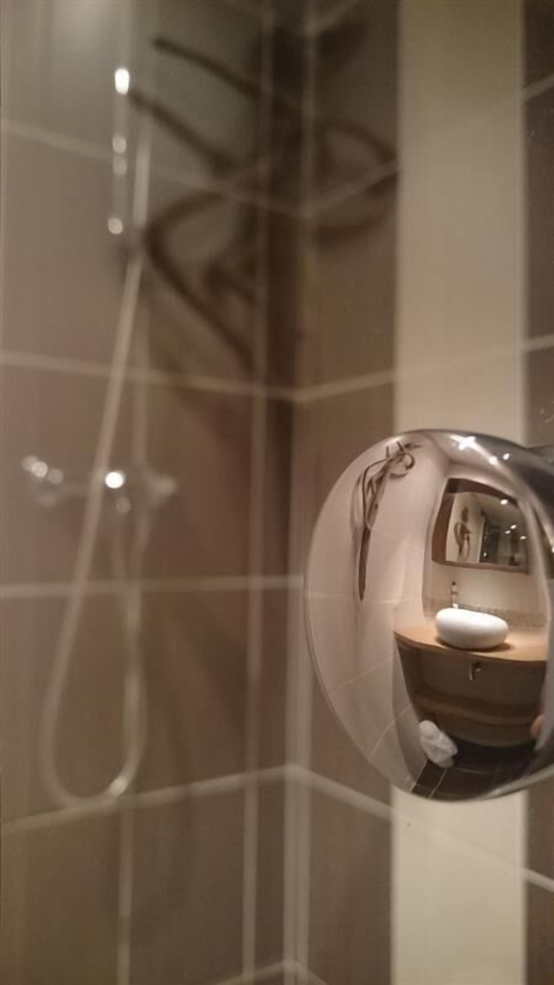 A bathroom with a mirror reflecting a sink and a toilet.