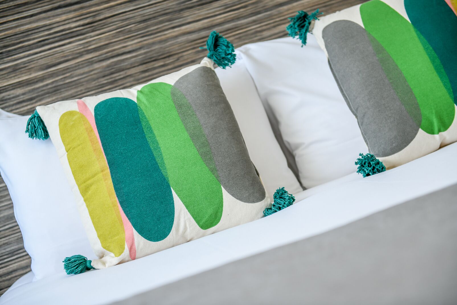 Un canapé blanc agrémenté de coussins colorés aux motifs abstraits et aux franges.