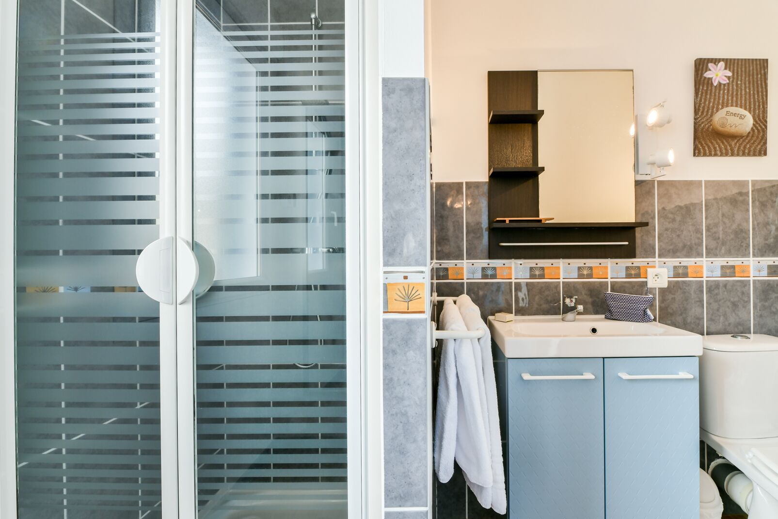 Ein Badezimmer mit Duschkabine, Waschbecken mit Spiegel und Toilette.