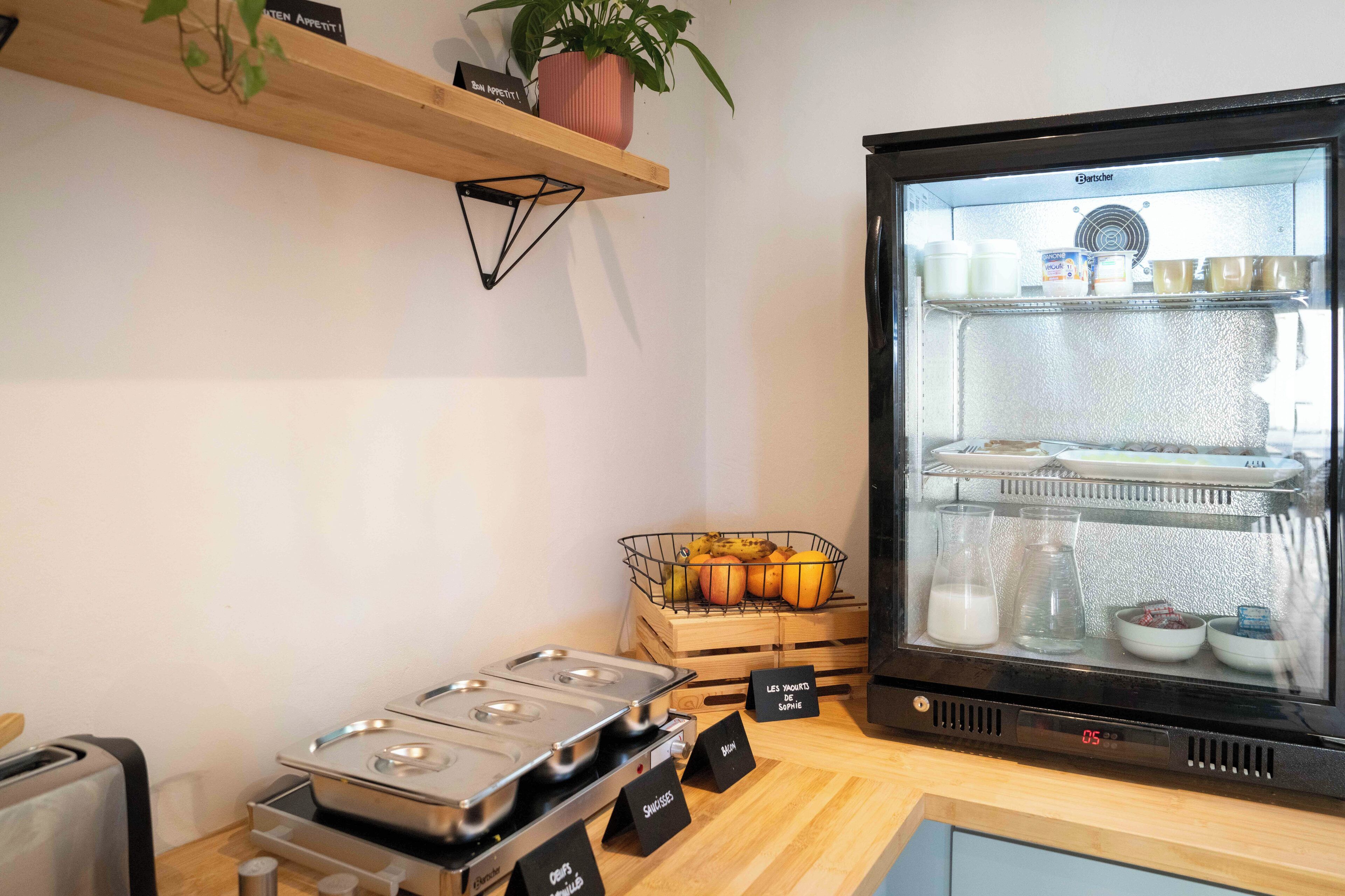 Une petite cuisine équipée d’un réfrigérateur, d’une cuisinière et d’un panier de fruits.