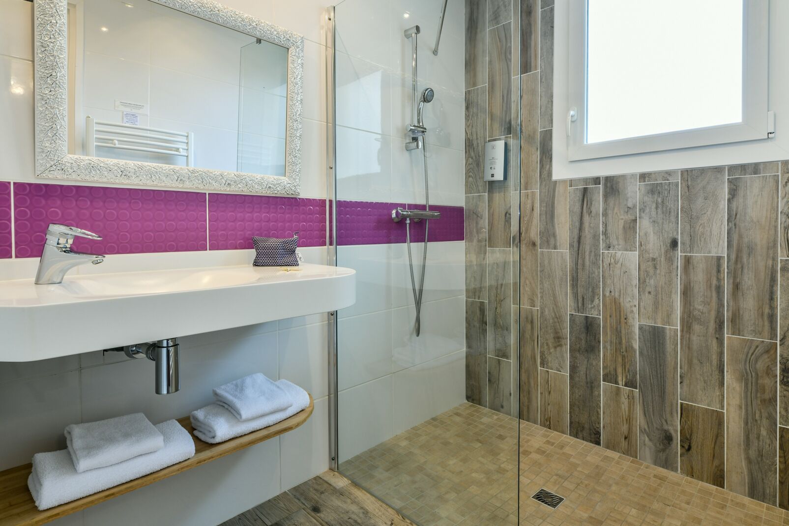 Een moderne badkamer met een witte wastafel, een douchecabine van glas en een houten vloer.