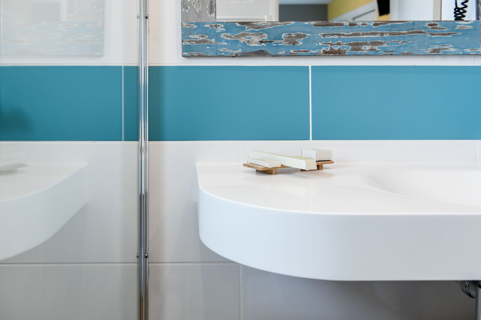 Une salle de bain avec deux lavabos, une douche en verre et un mur recouvert de carreaux bleus et blancs.