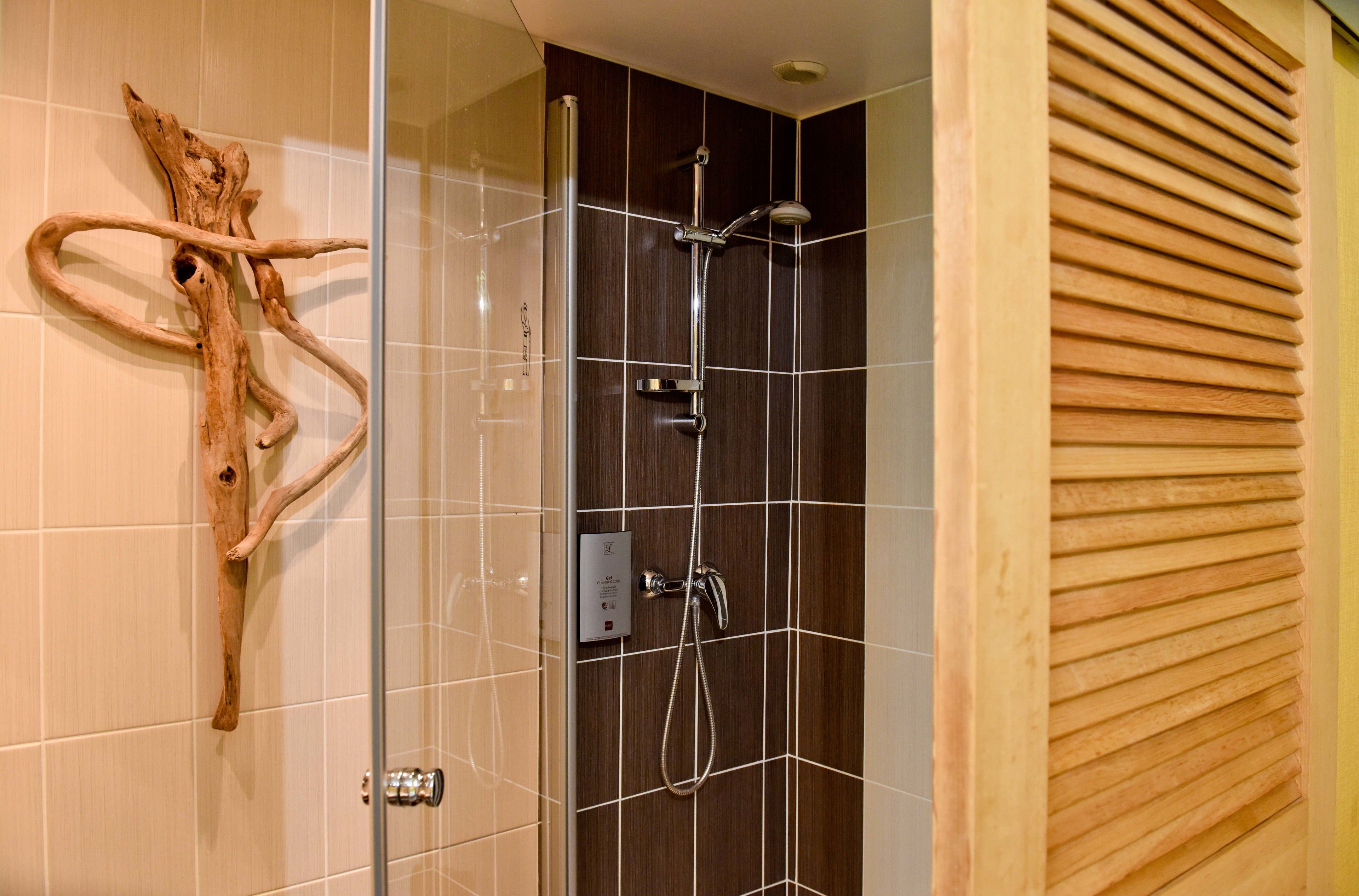 Ein modernes Badezimmer mit Duschkabine aus Glas, Wanddeko aus Holz und Fliesenboden.