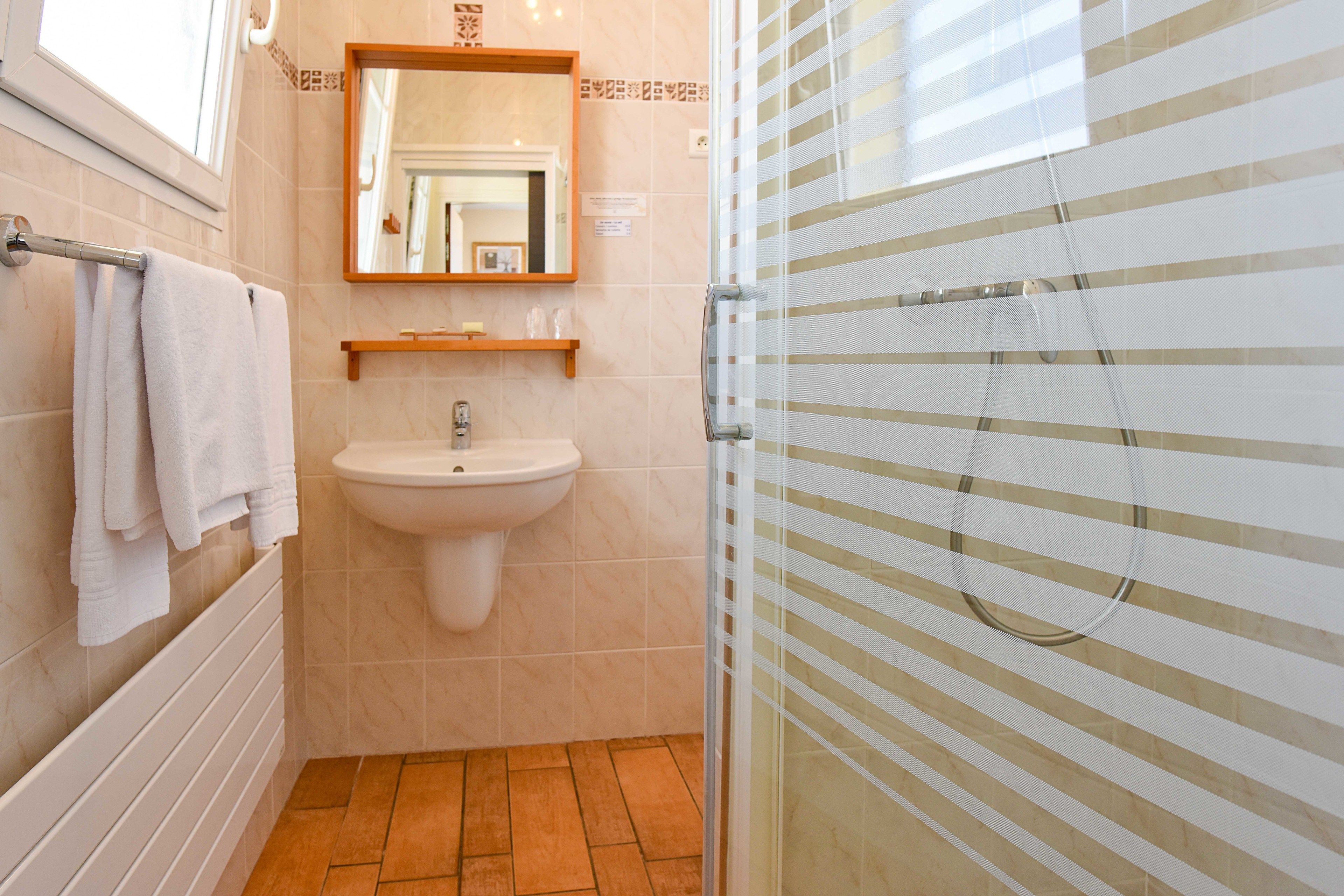 A bathroom with a sink, mirror, towel rack, and shower enclosure.