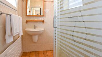 A bathroom with a sink, mirror, towel rack, and shower enclosure.