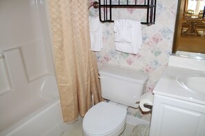 Un baño con inodoro, bañera, cortina de ducha y barra para toallas.