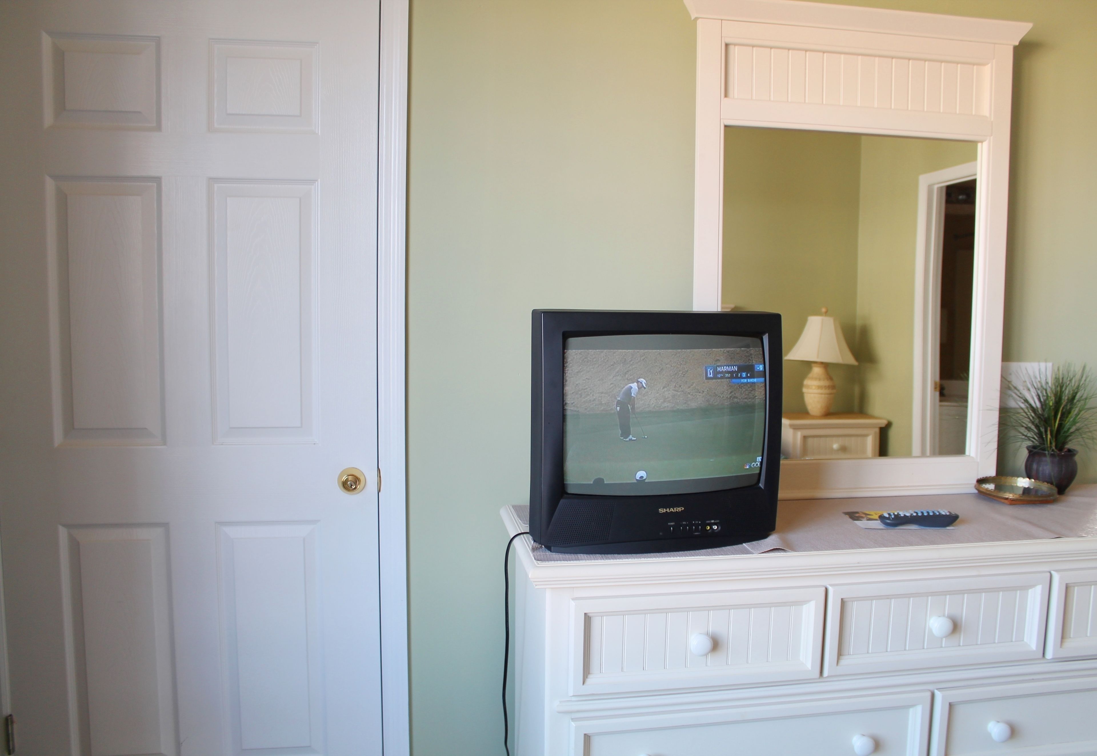 Une télévision posée sur une commode, diffusant un match de golf.
