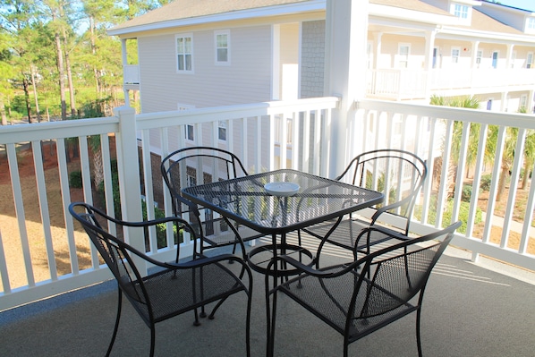 A balcony with a table and chairs, overlooking a residential area with houses and trees.