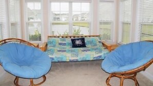A room with a bed, two blue chairs, and large windows with blinds. - 3804 Bay Village (North Myrtle Beach)