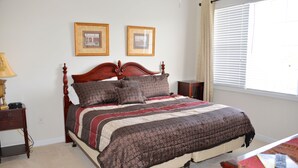 A neatly made bed with a patterned bedspread, a wooden headboard, and two framed pictures on the wall. - 434 Ironwood (North Myrtle Beach)