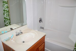 Un baño con lavamanos, espejo y bañera.