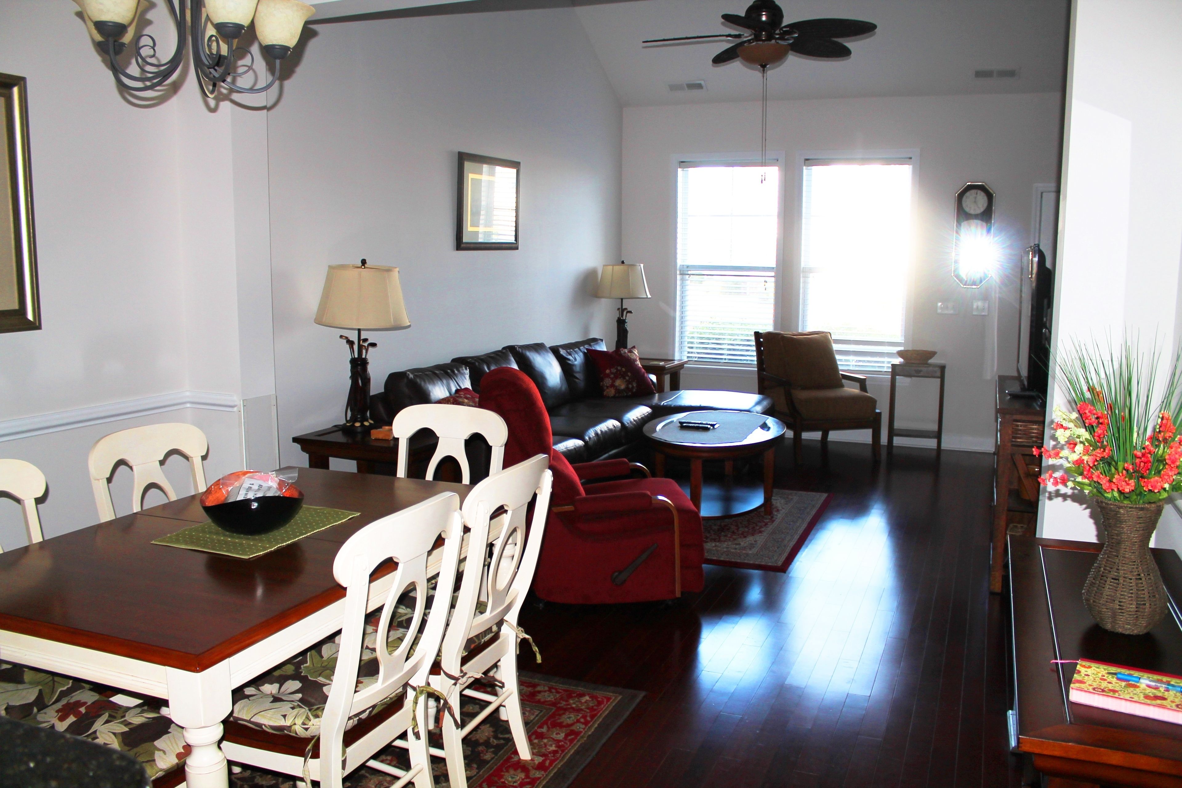 A living room with a dining table, chairs, a sofa, a coffee table, and a TV.