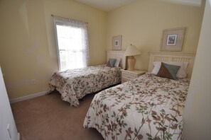 A bedroom with two beds, a nightstand, a lamp, and two framed pictures on the wall. - 213 River Crossing (North Myrtle Beach)