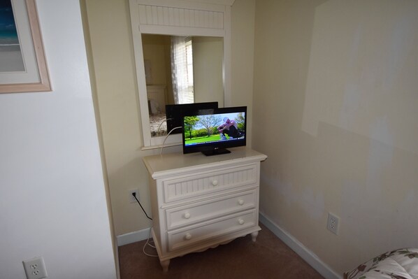 A room with a white dresser, a television on top, and a mirror above it. - 213 River Crossing (North Myrtle Beach)