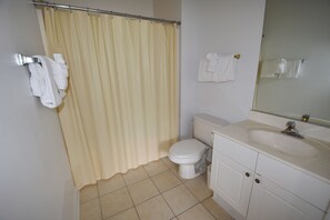 A bathroom with a toilet, sink, and shower curtain. - 213 River Crossing (North Myrtle Beach)