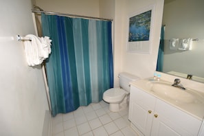 A bathroom with a toilet, sink, and shower curtain.