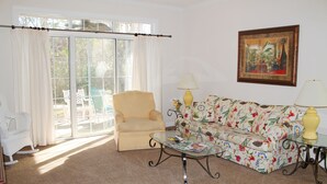 A living room with a sofa, armchair, glass coffee table, and two lamps. - 214 Wedgewood (North Myrtle Beach)