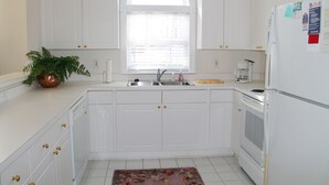 A kitchen with white cabinets, a window, a sink, a stove, and a refrigerator. - 214 Wedgewood (North Myrtle Beach)