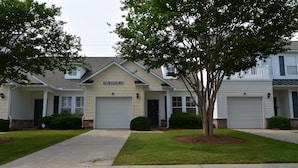 A row of townhouses with a central garage, a sign reading "The Havens 23", and a well-maintained lawn. - 2314 The Havens (North Myrtle Beach)