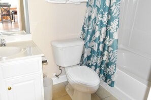 A bathroom with a toilet, sink, and shower curtain.