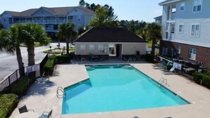 A rectangular swimming pool with a small deck area, surrounded by palm trees and a few lounge chairs. - 522 Cypress Bend (North Myrtle Beach)