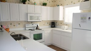 A kitchen with white cabinets, a microwave, a stove, a sink, and a refrigerator. - 622 Willow Bend (North Myrtle Beach)