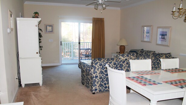 A living room with a white table, patterned sofa, and a white refrigerator. - 622 Willow Bend (North Myrtle Beach)