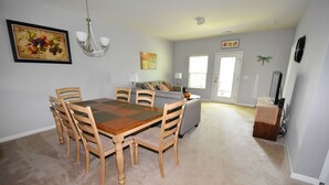 A dining area with a wooden table and chairs, a sofa, and a television in the background. - 722 Willow Bend (North Myrtle Beach)