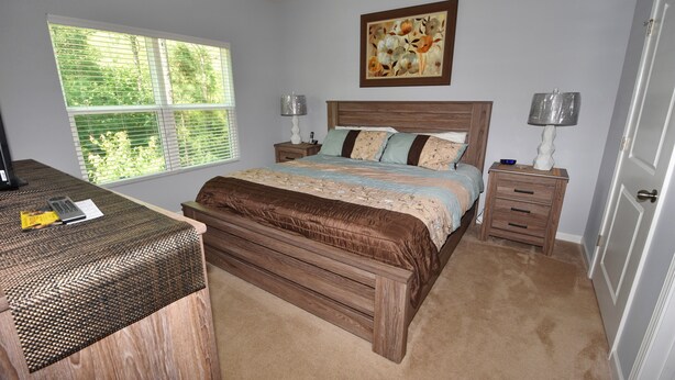 A bedroom with a large bed, two bedside tables, a desk, and a window with blinds. - 722 Willow Bend (North Myrtle Beach)