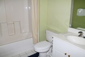 A bathroom with a white toilet, a bathtub, and a sink with a mirror above it. - 633 Cypress Bend (North Myrtle Beach)