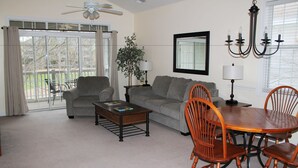 A living room with a gray sofa, a coffee table, and wooden chairs around a small table. - 534 Wedgewood (North Myrtle Beach)