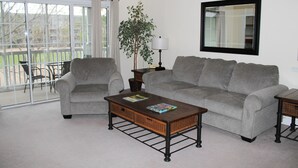 A living room with two grey sofas, a wooden coffee table with magazines, a floor lamp, and a potted plant. - 534 Wedgewood (North Myrtle Beach)