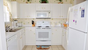 A kitchen with white cabinets, a microwave, stove, and refrigerator. - 713 Ironwood (North Myrtle Beach)