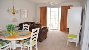 A dining area with a round table, chairs, and a chandelier. There is a sofa and a chair with a cushion. A white cabinet is against the wall. - 713 Ironwood (North Myrtle Beach)