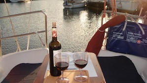Un barco con una botella de vino y dos copas sobre una bandeja de madera.