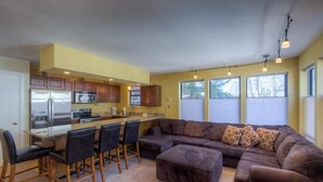 A modern kitchen with a central island, bar stools, and a large L-shaped sectional sofa. - Boomerang Lodge 5 2 Bedroom Condo By Accommodations in Telluride (Telluride)