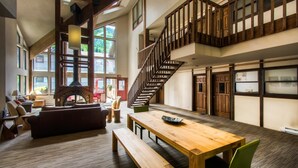 A spacious living area with a wooden staircase, large windows, and a fireplace. - Boomerang Lodge 5 2 Bedroom Condo By Accommodations in Telluride (Telluride)