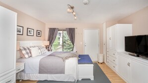A bedroom with a bed, bedside tables, a TV, a wardrobe, and a window with curtains.