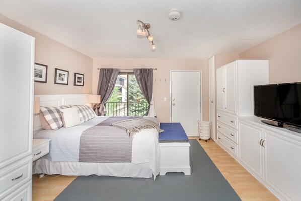 A bedroom with a bed, bedside tables, a TV, a wardrobe, and a window with curtains.