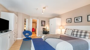 A bedroom with a bed, a desk, a chair, a television, and a wardrobe.