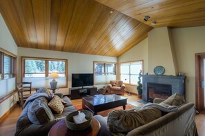 Un salon spacieux avec un haut plafond, une cheminée, un téléviseur et des sièges confortables.