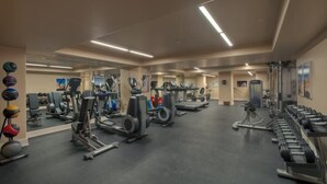Ett gym med olika typer av träningsredskap, speglar och ställ för vikter.