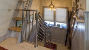 Een meerlaags interieur met een trap, een kroonluchter en een raam met jaloezieën.