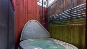A small, enclosed hot tub with a control panel, surrounded by wooden walls.