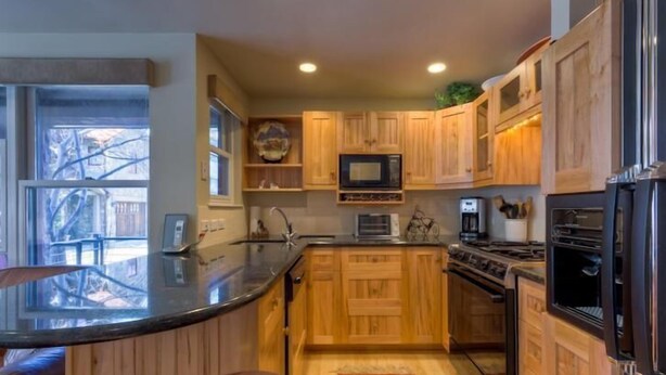 A kitchen with wooden cabinets, a microwave, stove, and refrigerator.