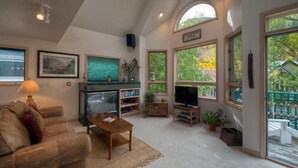 A spacious living room with a high ceiling, large windows, a fireplace, and a cozy seating area. - Madison Pacific 1 Bedroom Condo By Accommodations in Telluride (Telluride)